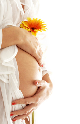 pregnant woman holding her belly and flower