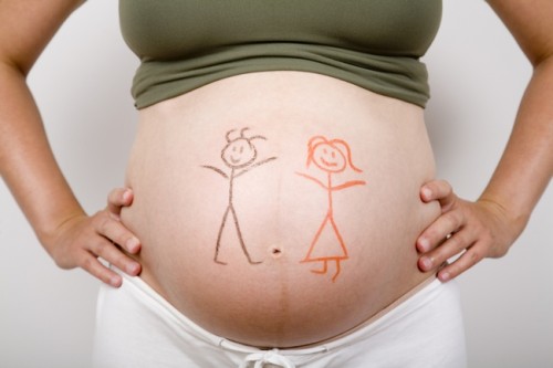 Pregnant woman with a boy and a girl painted in her belly.