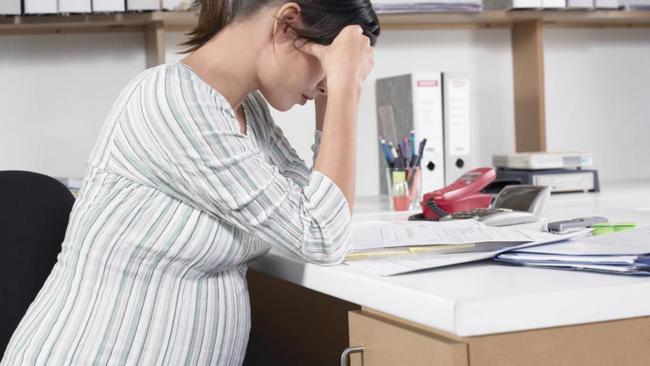 Young pregnant woman sitting at desk looking at document, side view