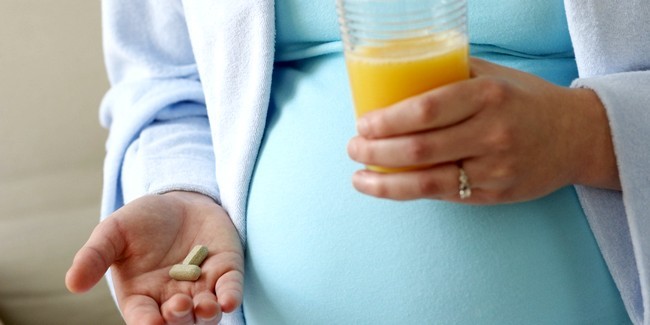Pregnant woman holding vitamin pills and orange juice