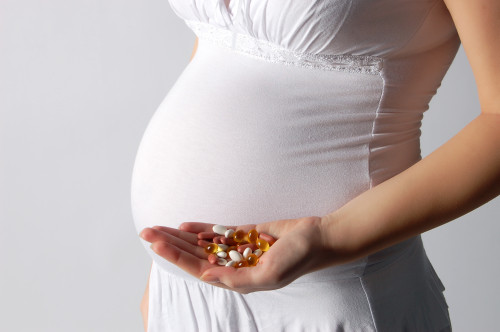 Pregnant woman holding tablets isolated