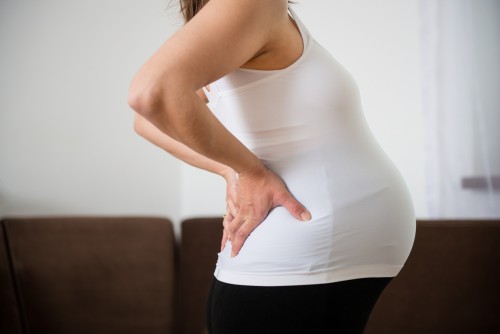 Torso of pregnant woman with backache - holding back