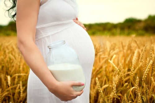 Беременная женщина с банкой молока в поле
