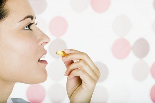 Woman taking vitamin --- Image by © Steve Hix/Somos Images/Corbis