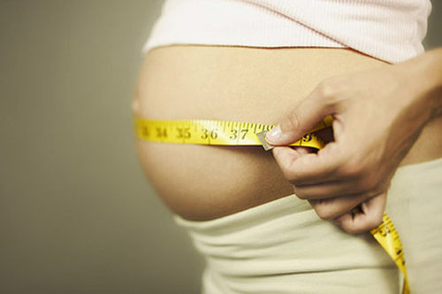 Cropped pregnant woman measuring waist