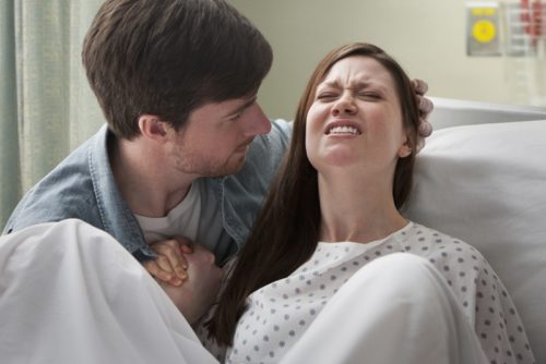 Caucasian man helping girlfriend deliver baby