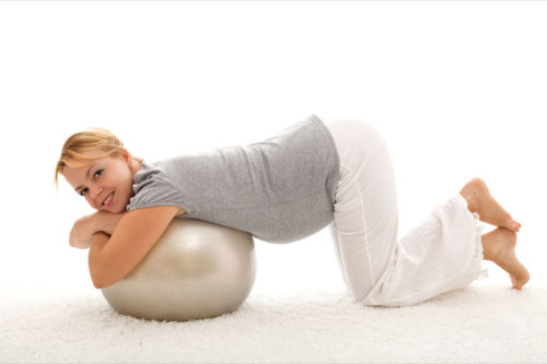 Beautiful woman exercising with large ball